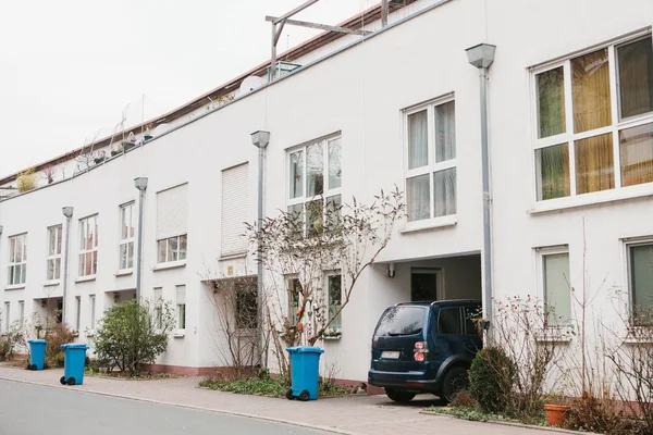 Çalılar ve çöp kutuları ve park edilmiş araba ile güzel beyaz iki katlı ev. Almanya. — Stok fotoğraf