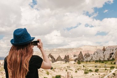 Bir turist kız telefonda hills Kapadokya Türkiye'de güzel bir manzarasına anısına bir fotoğraf yapar. Seyahat, turizm, hiking tatil.