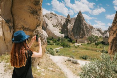 Bir turist kız telefonda hills Kapadokya Türkiye'de güzel bir manzarasına anısına bir fotoğraf yapar. Seyahat, turizm, hiking tatil.