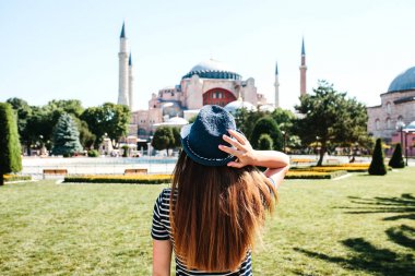 Istanbul, Türkiye'de ünlü Aya Sofya Camii yanındaki Sultanahmet Meydanı'nda arkadan şapkalı bir genç kız gezgin. Seyahat, turizm, gezi.