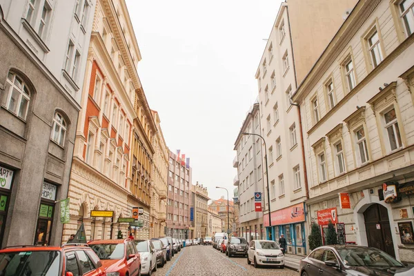 Praga, 13 de diciembre de 2016: Hermosa calle de Praga con arquitectura antigua, adoquines, letreros publicitarios y numerosos aparcamientos de coches a lo largo de las casas — Foto de Stock