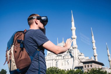 Sanal gerçeklik gözlüklü bir gezgin. Dünyanın dört bir yanından sanal seyahat kavramı. Arka planda Türkiye'de Istanbul'da Sultanahmet Camii. Geleceğin teknolojisi kavramı.