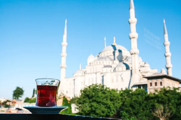 Traditionella aromatiska turkiska svart te i en tulip-formade glas. I bakgrunden kallas även blåttmoskén Sultanahmet i Istanbul, Turkiet. — Stockfoto