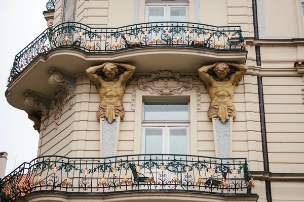 Arquitectura europea. Primer plano - esculturas - columnas en forma de personajes antiguos de apoyo balcón - fachada del edificio histórico vintage . — Foto de Stock