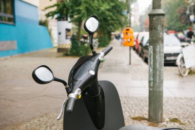 Ön planda mevcuttur bir elektrikli scooter direksiyon arka Berlin Caddesi kentsel bir görünümüdür.
