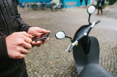 Turist mobil uygulaması ile elektrikli scooter telefondaki kullanın ve klemple etkinleştirmek için gidiyor. Berlin ve Paris'te popüler bir araç.