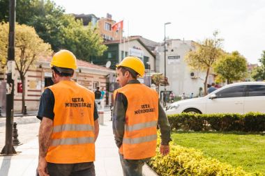 Istanbul, 16 Haziran 2017: İki bilinmeyen erkekler iş elbiseleri - Koruyucu baretler ve sarı yelek güneşli şehir yürüyor