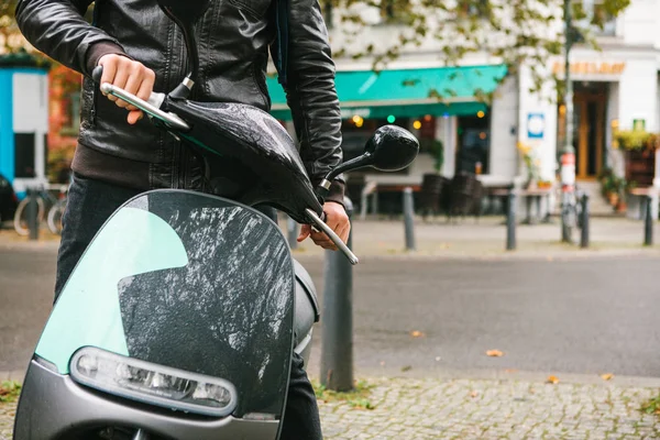 The tourist boarded an electric scooter. A popular vehicle in the city is called an electric scooter. In the background a street in Berlin.