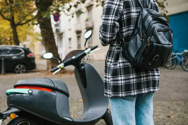 Ein Tourist mit einem Rucksack wird einen Elektroroller über eine mobile Anwendung im Telefon benutzen und ihn distal aktivieren. ein beliebtes fahrzeug in berlin und paris. — Stockfoto