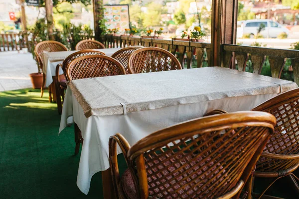 Vista de la cafetería de verano abierta vacía con sillas de mimbre y muebles de madera junto a macetas con plantas y flores . —  Fotos de Stock