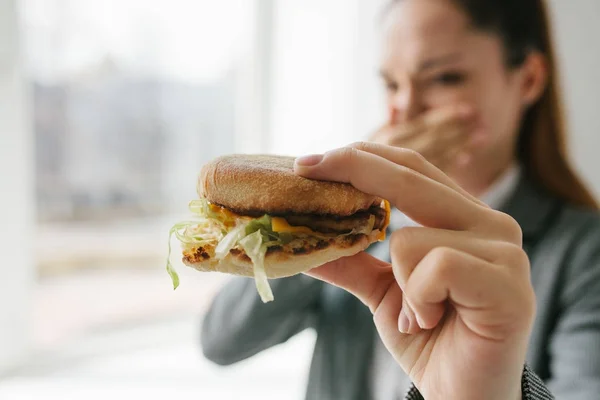 A young girl shows that she does not like a burger. Conceptual image of refusal from unhealthy eating. — Stock Photo, Image