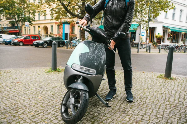 De toerist aan boord van een elektrische scooter. Een populair voertuig in de stad heet een elektrische scooter. Op de achtergrond een straat in Berlijn. — Stockfoto