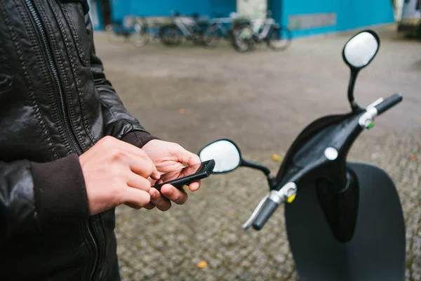 The tourist is going to use the electric scooter through the mobile application in the phone and distally activate it. A popular vehicle in Berlin and Paris. — Stock Photo, Image