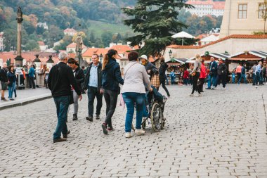 Prag, 28 Ekim 2017: Kimliği belirsiz bir kadın engelli kişi Prag Caddesi, Prag Kalesi'nin yanında turist dolu boyunca tekerlekli sandalyede taşıyan