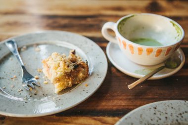 Bir kirli tabak ve boş bir fincan kahve. Yarısı yenmiş kek bir plaka üzerinde. Bir kafede ahşap bir masa üzerinde yedikten sonra boş yemekleri
