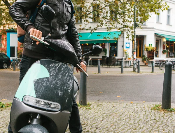 Турист сел на электрический скутер. Популярный автомобиль в городе называется электрическим скутером. На заднем плане улица в Берлине . — стоковое фото