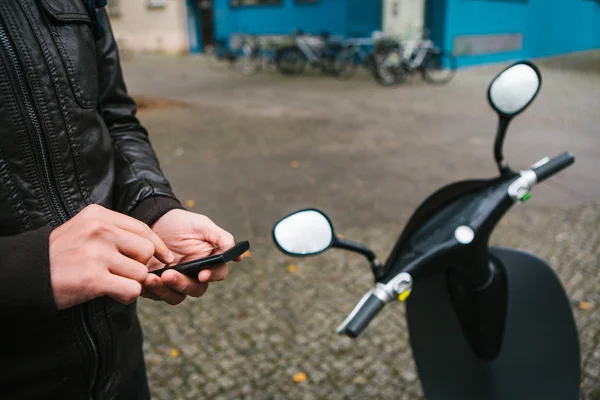 Турист собирается использовать электрический скутер через мобильное приложение в телефоне и дистально активировать его. Популярный автомобиль в Берлине и Париже . — стоковое фото