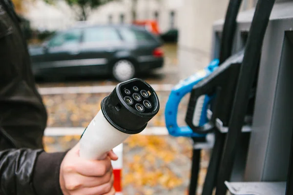 The driver picks up a cable to charge the electric vehicle. A modern and eco-friendly mode of transport that has spread throughout the world. — Stock Photo, Image