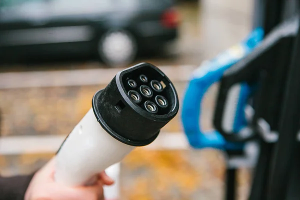 The driver picks up a cable to charge the electric vehicle. A modern and eco-friendly mode of transport that has spread throughout the world. — Stock Photo, Image