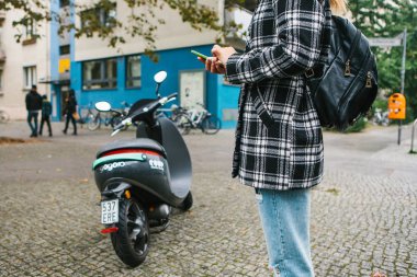 Berlin, 1 Ekim 2017: cep telefonu uygulaması harekete geçirmek Escooter. Bir turist bir mobil uygulaması aracılığıyla bir elektrikli scooter telefondaki kullanın ve klemple etkinleştirmek için gidiyor.