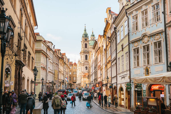 A beautiful street of Prague, Czech Republic. Tourists and locals walk. Near the building with shops.