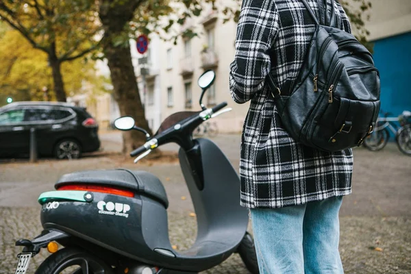Берлин, 1 октября 2017 года: Escooter активировался через мобильное приложение. Турист собирается использовать электрический скутер через мобильное приложение в телефоне и дистально активировать его . — стоковое фото
