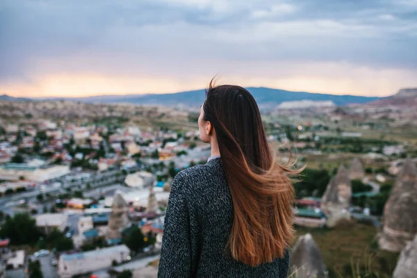 Toeristische van de jonge vrouw van een hoog punt kijken naar de zonsondergang over de stad van Goreme in Cappadocië in Turkije en dromen. — Stockfoto