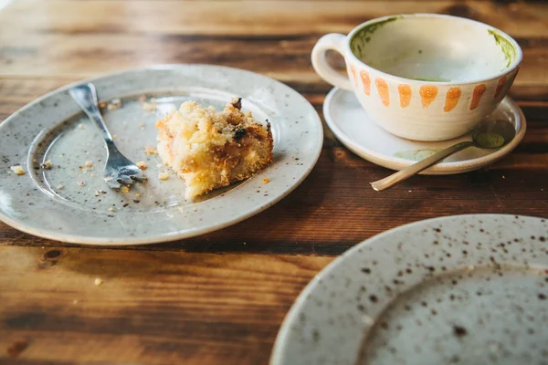 A dirty plate and an empty cup of coffee. The half-eaten cupcake on a plate. Empty dishes after eating on a wooden table in a cafe — Stock Photo, Image