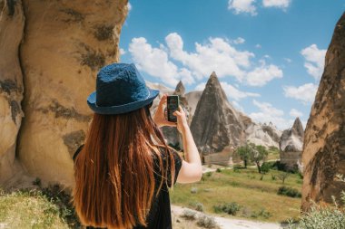 Bir turist kız telefonda hills Kapadokya Türkiye'de güzel bir manzarasına anısına bir fotoğraf yapar. Seyahat, turizm, hiking tatil.