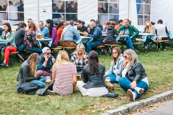 Prag, 23 Eylül 2017: Oktoberfest Çek Republic.Young kız konuşuyor ve taze bira içme çimenlerin üzerinde oturan arkadaşlar denilen geleneksel Alman Bira Festivali kutlama