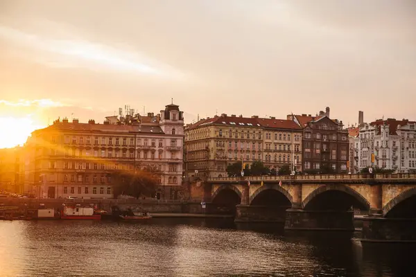 Schöne Aussicht auf die Architektur Prags bei Sonnenuntergang. Traditionelle Häuser und eine Brücke über den Fluss. — Stockfoto
