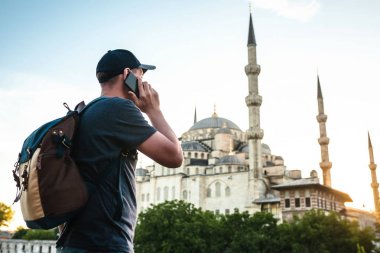 Erkek Gezgin Sultanahmet Camii - Istanbul 'un ünlü turistik cazibe yakınındaki bir cep telefonu konuşurken bir sırt çantası ile. Seyahat, turizm, gezi.