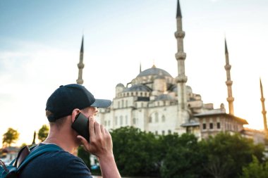 Erkek Gezgin Sultanahmet Camii - Istanbul 'un ünlü turistik cazibe yakınındaki bir cep telefonu konuşurken bir sırt çantası ile. Seyahat, turizm, gezi.