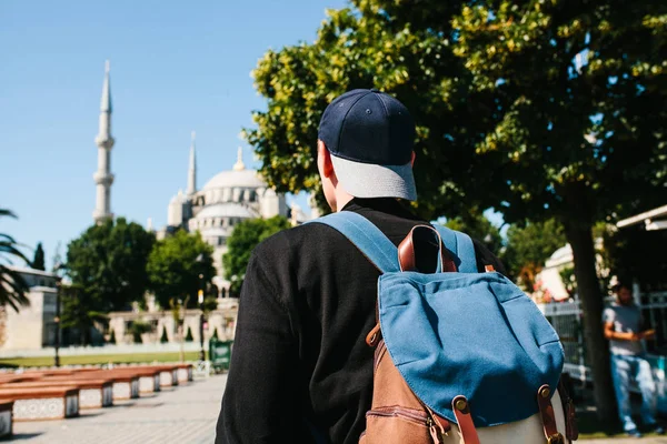 A man in a baseball cap with a backpack next to the blue mosque is a famous sight in Istanbul. Travel, tourism, sightseeing. — Stock Photo, Image