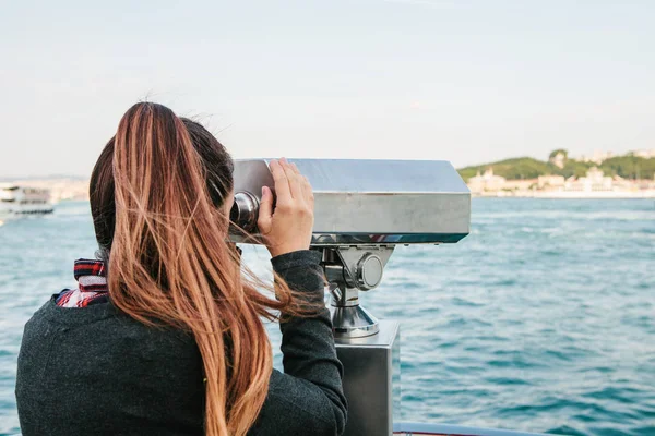 Chica mirando al mar a través del telescopio turístico. Vista del Bósforo en Estambul, Turquía . — Foto de Stock