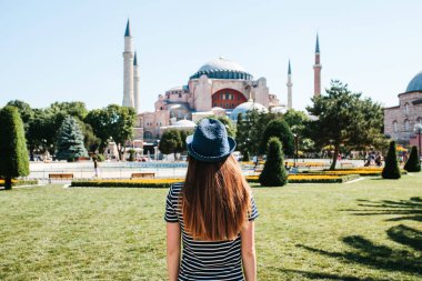 Istanbul, Türkiye'de ünlü Aya Sofya Camii yanındaki Sultanahmet Meydanı'nda arkadan şapkalı bir genç kız gezgin. Seyahat, turizm, gezi.