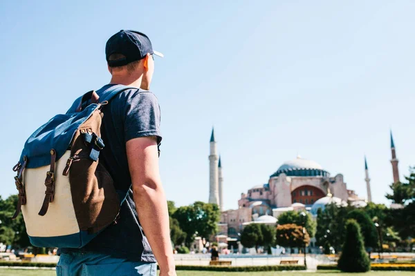 A traveling man with a backpack in Sultanahmet Square near the famous Aya Sofia mosque in Istanbul in Turkey. Travel, tourism, sightseeing. — Stock Photo, Image