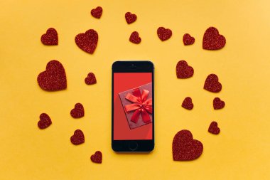 Üstten Görünüm. Üstünde belgili tanımlık telefon perde bir hediye. Yakınlarda sarı bir arka plan üzerinde bir kalp şeklinde semboller bulunmaktadır.