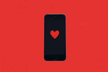 Üstten Görünüm. Kalp kırmızı bir arka plan üzerinde yatıyor telefon ekranında.