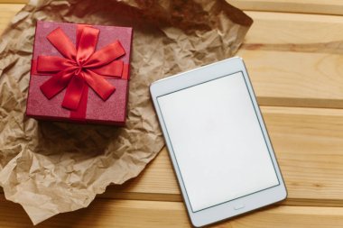 Hediye yanındaki ahşap yüzeyde tablet ile boş bir perde olduğunu.