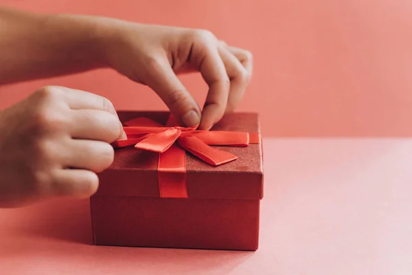 The girl has received a gift in a beautiful red box with a ribbon and is going to open it. — Stock Photo, Image