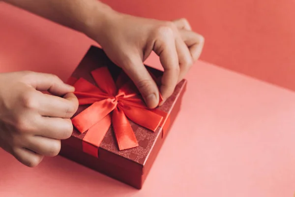 La chica ha recibido un regalo en una hermosa caja roja con una cinta y va a abrirlo . — Foto de Stock