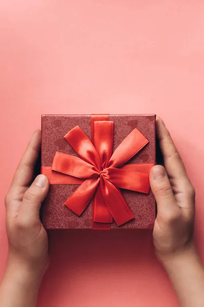 La chica ha recibido un regalo en una hermosa caja roja con una cinta y va a abrirlo . — Foto de Stock