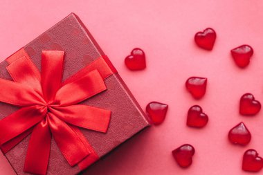 Şerit ve yay kırmızı zemin üzerine kırmızı güzel kutu. Yakınlarda bir kalp şeklinde semboller bulunmaktadır.