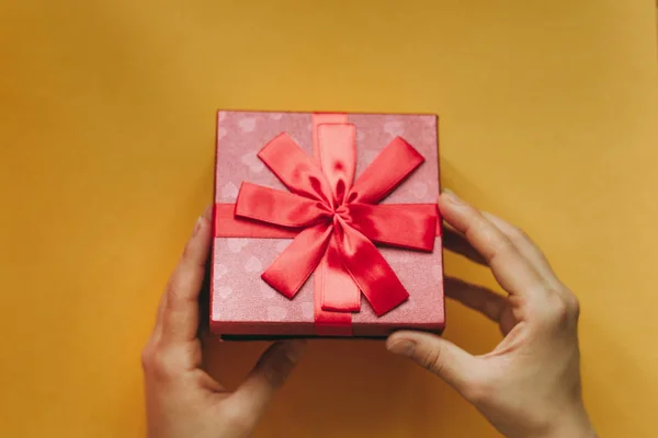 La chica ha recibido un regalo en una hermosa caja roja con una cinta y va a abrirlo . — Foto de Stock