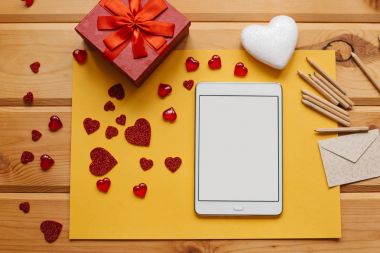 Boş bir ekran ile tablet hediye yanındaki ahşap yüzey üzerindedir. Yaratıcı çalışma alanı. Tatil hazırlanma.