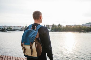 Avrupa'nın Çek Cumhuriyeti Prag evlerin zemin üzerine Nehri yanındaki bir sırt çantası ile turist adam sahanın. Seyahat, gezi, turizm.