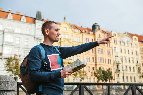 Турист с рюкзаком на фоне старой архитектуры в Праге в Чешской Республике. Он смотрит на карту. Он показывает свою руку на интересном аттракционе . — стоковое фото