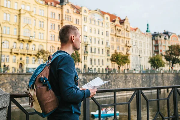 Un turista con uno zaino sullo sfondo della vecchia architettura a Praga nella Repubblica Ceca. Guarda la mappa. . — Foto Stock
