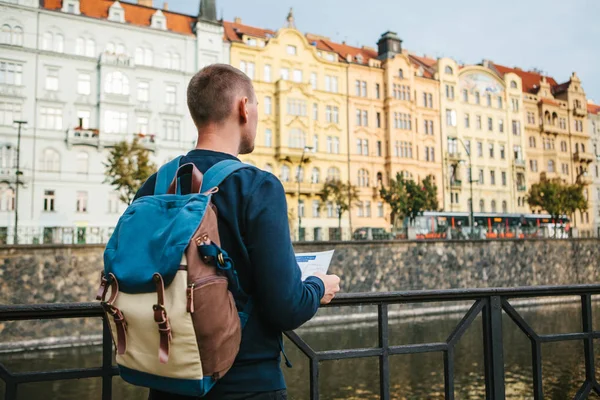 Turistický batoh na pozadí staré architektury v Praze v České republice. On se dívá na mapě. — Stock fotografie